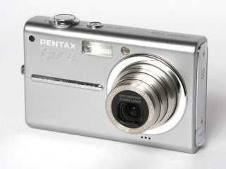 A silver Pentax Optio T20 digital camera placed on a white background, showing the lens extended and the front of the camera with branding visible.