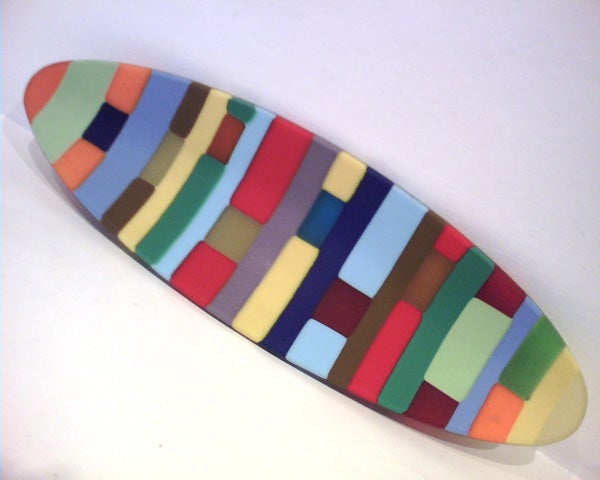Colorful surfboard-shaped object with a patchwork pattern of various solid colors.