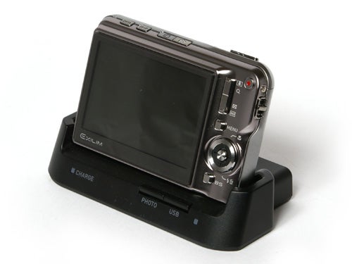 Casio Exilim EX-S770 digital camera mounted on its charging dock with a large LCD screen and control buttons visible on the back.