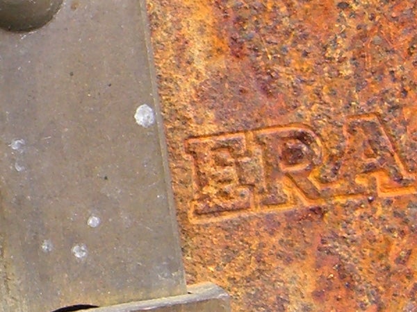 Close-up photo of a rusty surface with the letters 