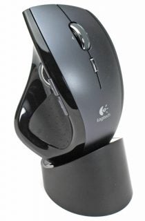 Logitech MX Revolution mouse positioned upright on a matching charging dock, featuring a black and silver design with the Logitech logo on the side.
