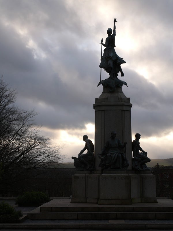 Silhouetted statue against cloudy sky.