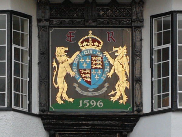 Coat of arms with a crowned shield flanked by two lions with the initials E and R and the date 1596 displayed on a building's facade.