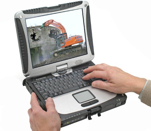 A person using a Panasonic ToughBook CF-19 with a construction excavator visible on the screen. The laptop is rugged with a handle and the screen is in the upright position.