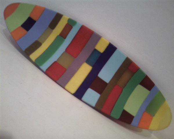 Colorful surfboard-shaped object with a multicolored pattern on a white background.