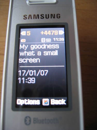 Samsung SGH-X830 mobile phone displaying a text message on its small screen with the date, 17/01/07, and time, 11:39, shown below, and the phone's brand at the top.