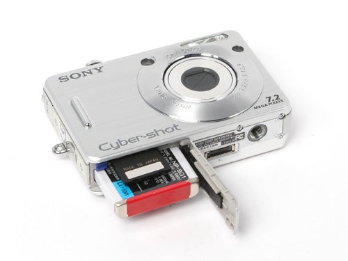 Sony CyberShot DSC-W70 digital camera with the battery compartment open showing the battery and memory card.