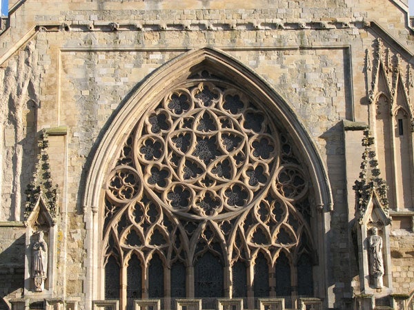 A detailed photo of a gothic church window with intricate stonework and patterned tracery.