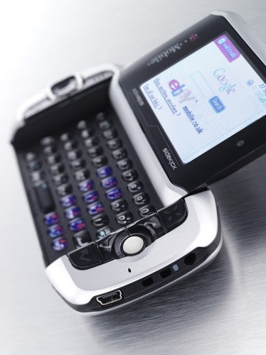 T-Mobile Sidekick 3 smartphone with swivel screen open to reveal a full QWERTY keyboard on a metal surface.