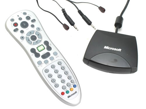 A Microsoft-branded media center remote control with various buttons including playback controls and a numeric keypad, alongside an IR receiver connected by a cable.
