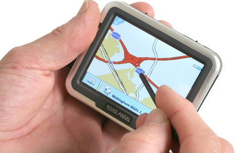 A person holding a Road Angel Navigator 6000 GPS device displaying a map with roads and navigation information.