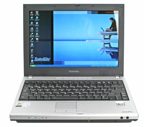 Toshiba Satellite U200-161 laptop open on a desk showing the desktop screen with a default wallpaper and taskbar icons, highlighting the Toshiba branding on the bottom of the display bezel.