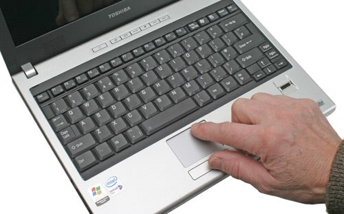 Close-up of a person using the Toshiba Satellite U200-161 laptop, showing the keyboard and touchpad with the Toshiba logo visible.