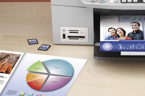 HP OfficeJet 6310 All-in-One printer with printed color graphics and photos on office desk, showcasing its print quality and multifunction capabilities.