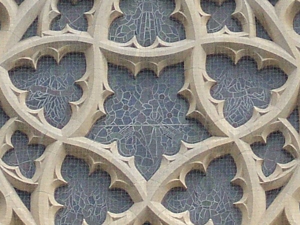 Stone architectural details showcasing the intricate patterns of a gothic window with quatrefoil designs.