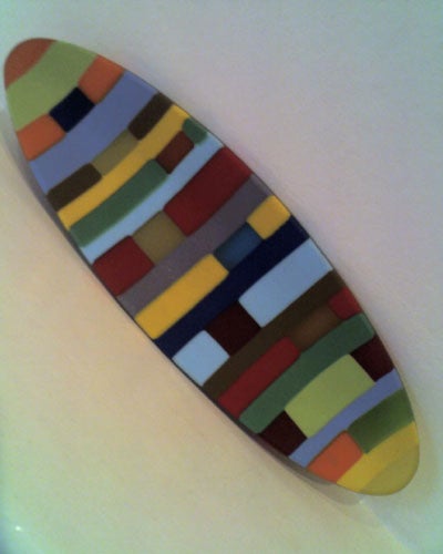Multicolored abstract patterned surfboard on a white background.
