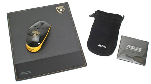 A Lamborghini-branded Asus wireless mouse in yellow and black, a matching Asus-branded mouse pad, a black pouch, and a small Asus booklet arranged on a light surface.