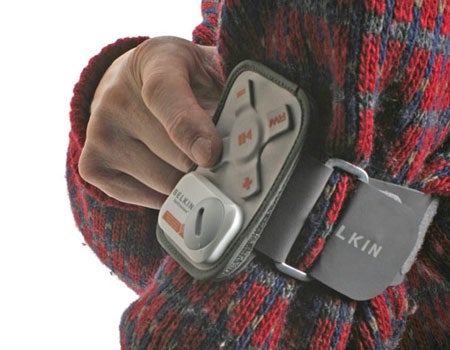 Person wearing a red and black patterned sweater holding a Belkin SportCommand remote control on their arm with visible control buttons.