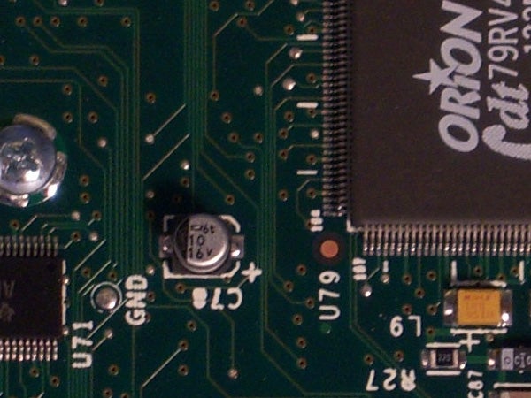 Close-up of a green circuit board with various electronic components such as capacitors, resistors, and integrated circuits.