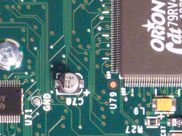 Close-up of a green circuit board featuring various electronic components including capacitors, integrated circuits, and printed circuit board traces, possibly from inside a digital camera like the Kodak EasyShare V803.