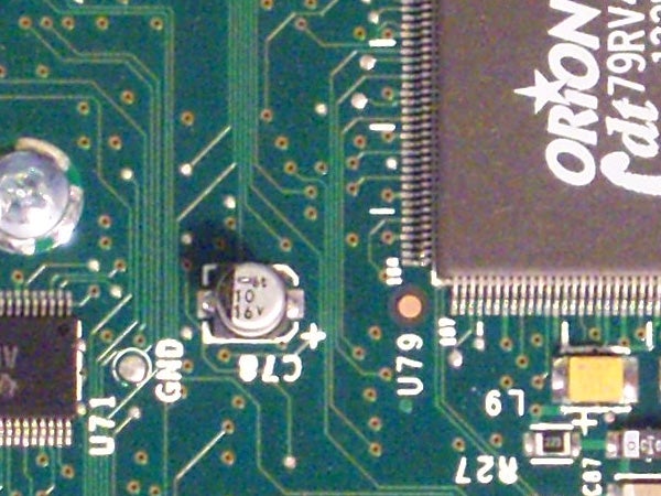 Close-up of a circuit board with various electronic components including capacitors, microchips, and printed circuitry, potentially from inside a Kodak EasyShare V803 camera or similar device.