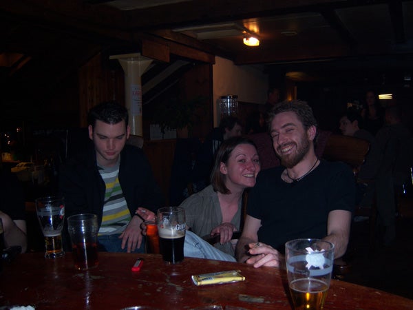 Three people enjoying a night out at a pub with drinks on the table.