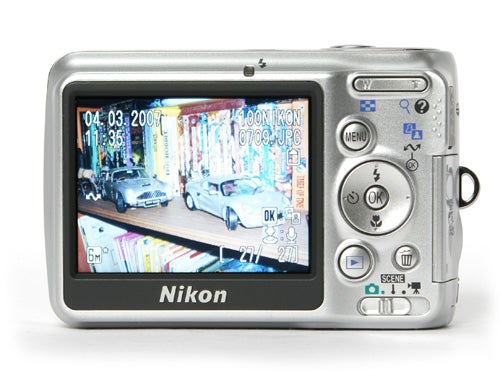 Nikon CoolPix L6 digital camera with a large LCD screen displaying a colorful street scene with cars and date timestamp.