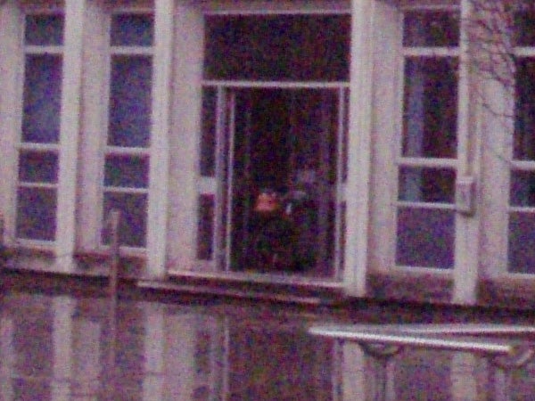 The image provided is a low-resolution photograph of a building with large windows. It is too grainy to discern any specific details about what might be inside the window or the exact nature of the building. It does not depict the Olympus mju 770 SW camera or any direct product review information such as the product itself, images taken with the product, or performance graphs.
