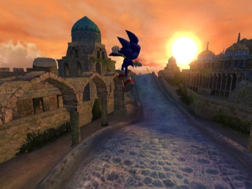 Sonic the Hedgehog character speeding along a curved pathway in the game Sonic and the Secret Rings, with a sunset and Middle-Eastern inspired architecture in the background.