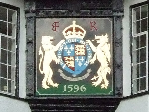 Coat of arms with a crown on top flanked by two standing lions against a green background, featuring a central shield with various heraldic symbols and the date 1596 at the bottom.