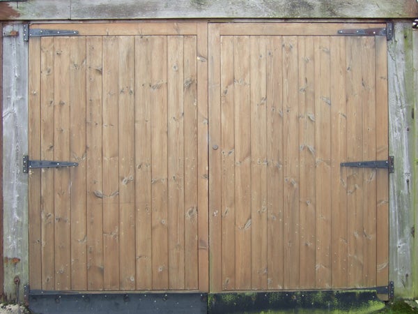 A wooden double-door gate with metal hinges and hardware detailing, showing natural textures and color details possibly captured by a Fujifilm FinePix F20 digital camera.