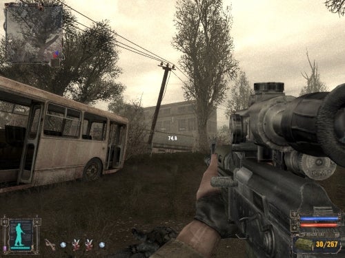 First-person viewpoint in the game S.T.A.L.K.E.R: Shadow of Chernobyl showing a character's hand holding a scoped rifle, a decrepit bus, and rundown buildings in a desolate landscape, with a heads-up display including health, armor status, and ammunition count.