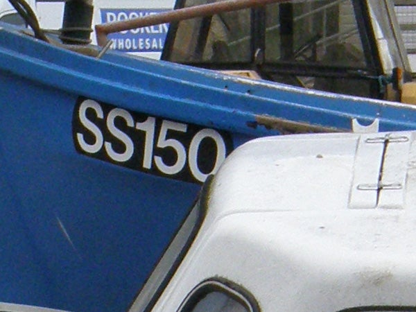Close-up photo of the side of a blue boat with the registration number 