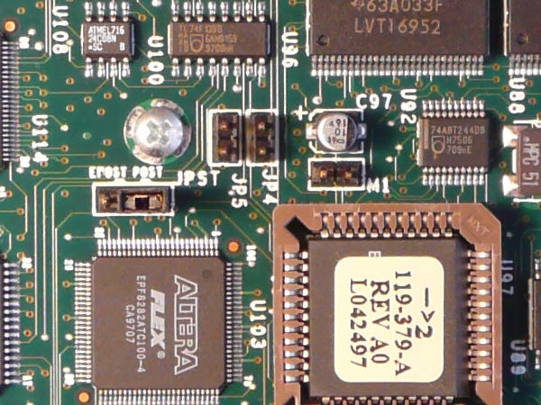 Close-up view of a green electronic circuit board featuring various integrated circuits, resistors, and capacitors, potentially showcasing internal components of the Panasonic Lumix DMC-TZ2 camera.