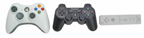 Three game controllers lined up, including a white Xbox 360 controller on the left, a black Sony PlayStation 3 DualShock controller in the center, and a white Nintendo Wii Remote on the right.