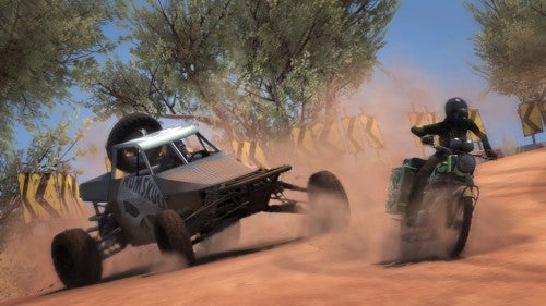 A screenshot from the video game Motorstorm showing a dynamic race scene with a buggy and a motorcycle competing on a dusty desert track.