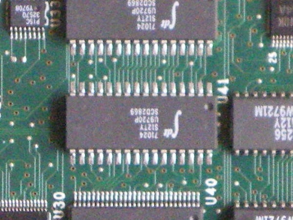 Close-up of a green circuit board featuring various integrated circuits, resistors, and connectors, highlighting electronic components typically found within digital cameras like the Pentax Optio M30.