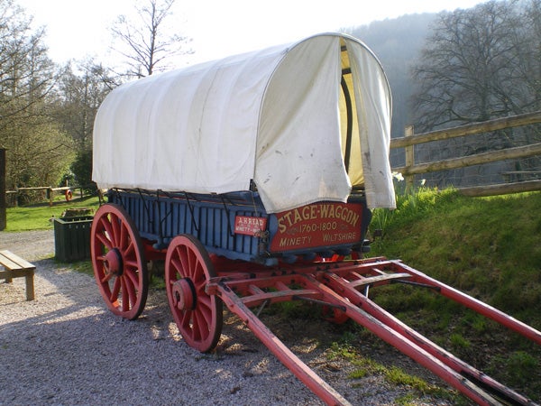 Vintage blue and red stage wagon with a white canvas cover, labeled 