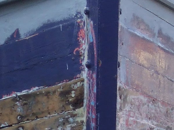 Image displaying close-up texture detail captured by the Fujifilm FinePix Z5fd camera, emphasizing the camera's macro photography capabilities with rich color saturation and fine detail on peeling paint and rust on a ship's hull.
