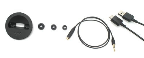 Sony Walkman NW-A805 accessories including a black circular charging dock, earbud tips of different sizes, and a USB and audio cable on a white background.