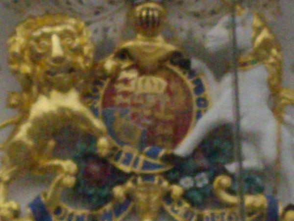 A blurry image of an ornate emblem with gold and jewel tones.