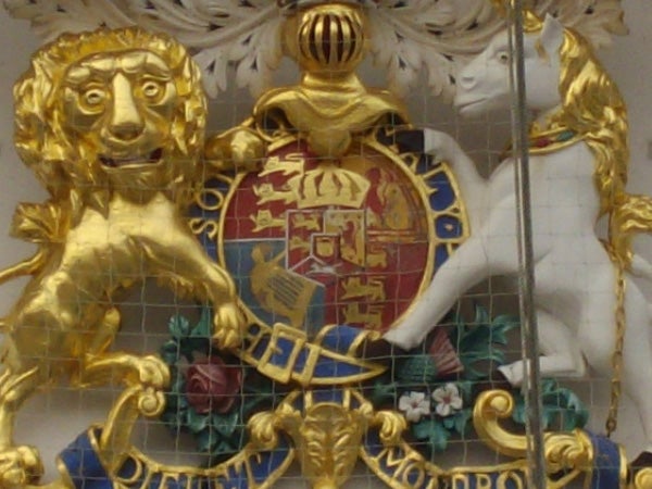 Ornate golden crest with lion and unicorn on a wall.