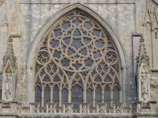 Detailed view of a Gothic style church window with intricate stone tracery and patterned glass panels.