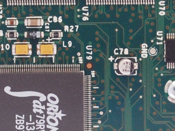 Close-up of a camera's electronic circuit board showcasing various components such as capacitors, resistors, and an integrated circuit labeled with the brand 