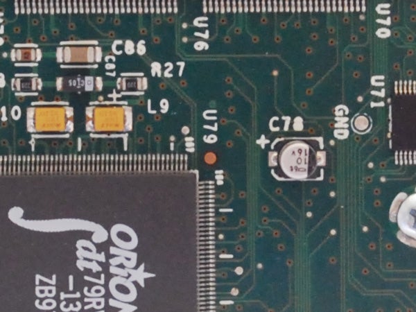 Close-up of a green circuit board with various electronic components including capacitors and a chip labeled 
