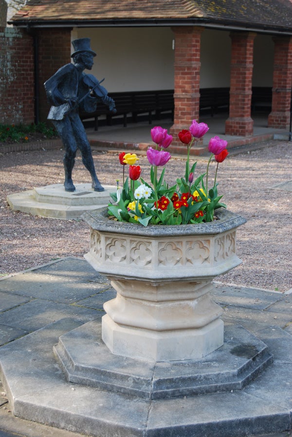 Photograph of colorful tulips in a stone planter with a bronze statue of a man in the background, captured with a Nikon D40x camera demonstrating depth of field and color reproduction.