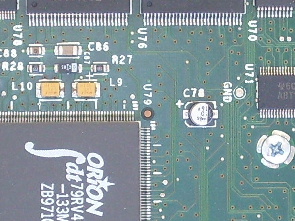 Close-up of a green circuit board with various electronic components including capacitors, resistors, and an integrated circuit labeled 