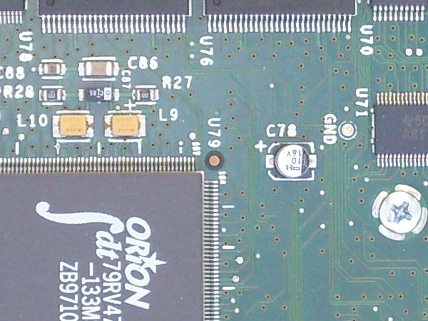 Close-up of a green circuit board with various electronic components including resistors, capacitors, and integrated circuits.