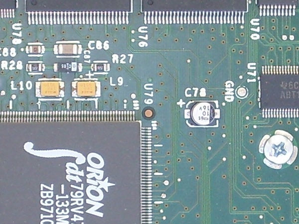 Close-up view of a green electronic circuit board with various components including resistors, capacitors, and a large integrated circuit labeled with 'Orton'.