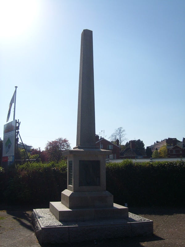 The image provided does not contain a Samsung L700 or any visual content directly related to product reviews, performance graphs, or the product perspective; instead, it shows a tall obelisk monument on a pedestal with plaques, located in a public area with green hedges around and a clear sky in the background.